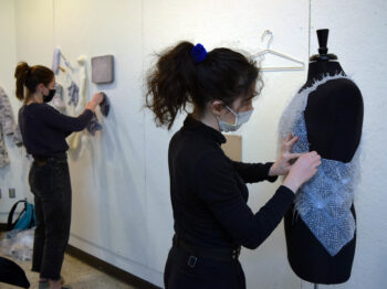 Students in full black outfits working with fabrics in class.