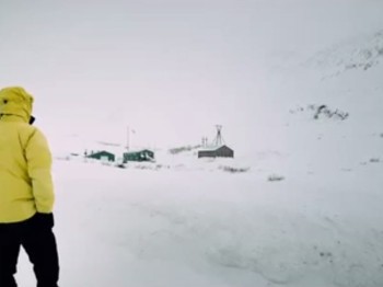 A man in a yellow jacket looks out at a snowy landscape.