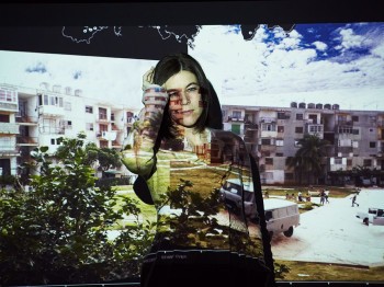 Projection of apartment buildings onto a woman and a screen.