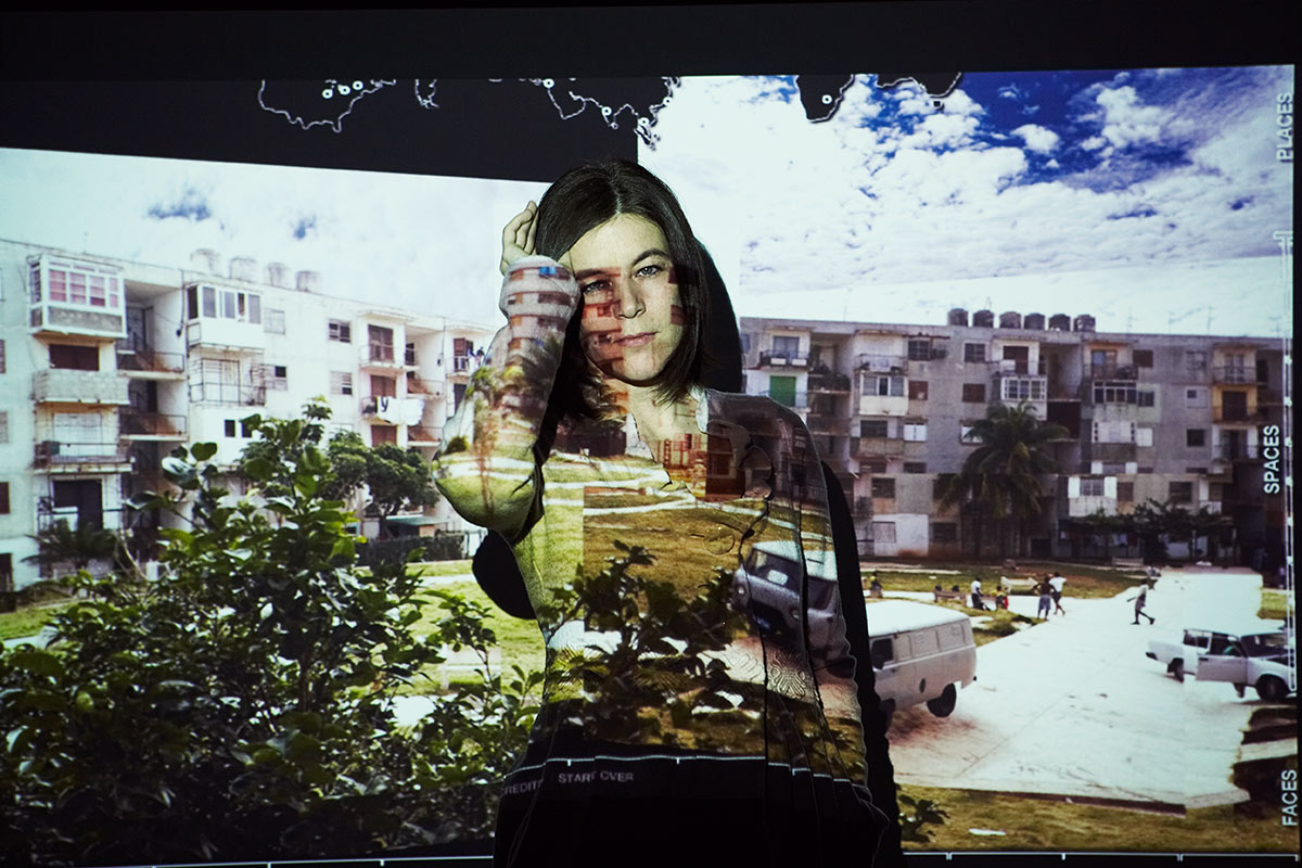 Projection of apartment buildings onto a woman and a screen.