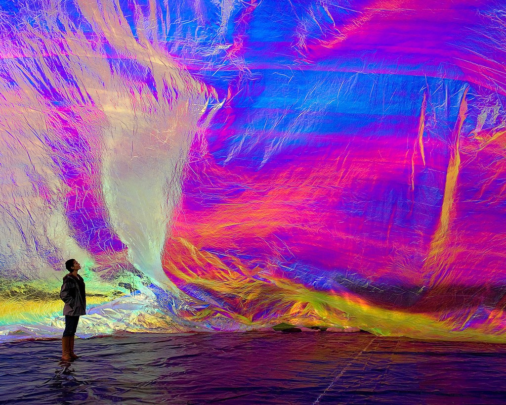A person stands next to a large, brightly colored piece of material which surrounds the space.