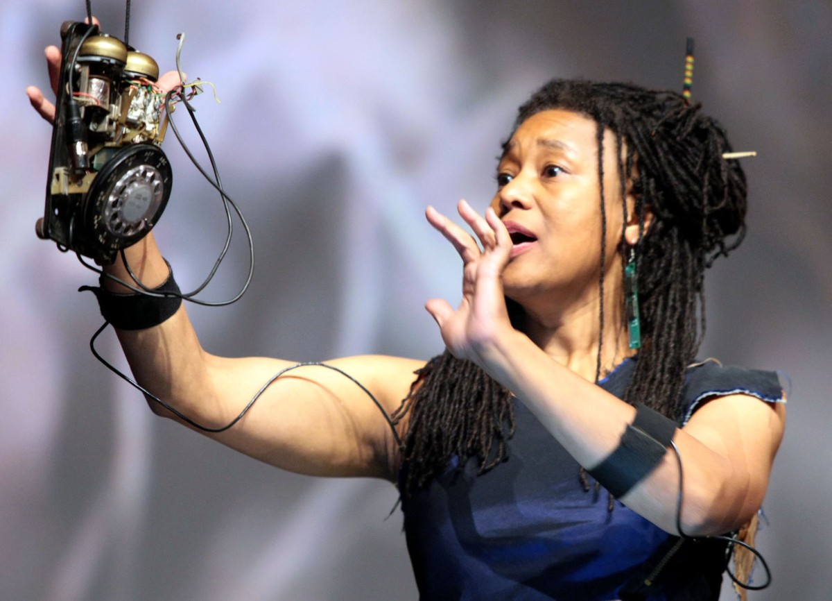 A woman performs while holding parts of a rotary phone.