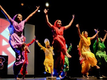 A group of students in colorful costumes perform a dance.
