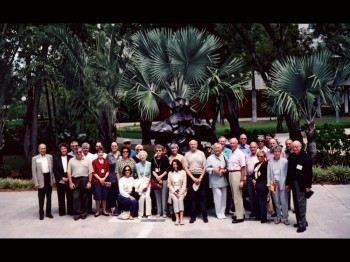 A group poses for a photo in front of palm trees.