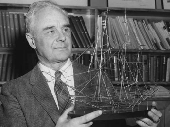 A man holds a model of a ship made of metal rods.