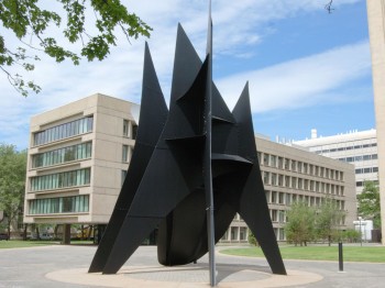 Large black metal sculpture on an outdoor plaza.