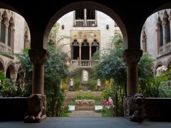 A courtyard filled with plants surrounded by an Italian cloister.