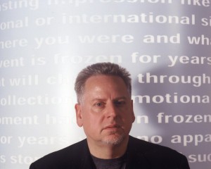 A man stands in front of a wall of projected text.