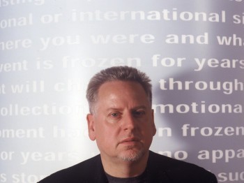 A man stands in front of a wall of projected text.
