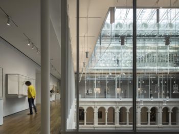 A second-floor gallery in a sun-lit atrium with classical arches.