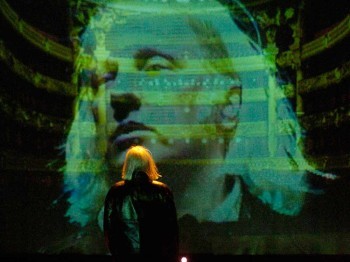 A person looks at a projected image of a man's face