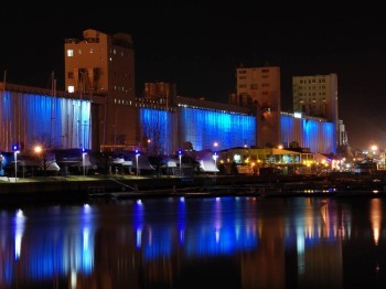 Buildings along a river are illuminated with blue light at night
