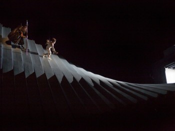 Two costumed performers walk down a long curving staircase