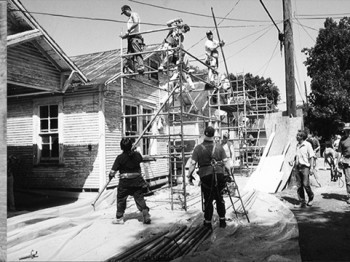 Three black and white photos of row houses and a construction crew working on them.