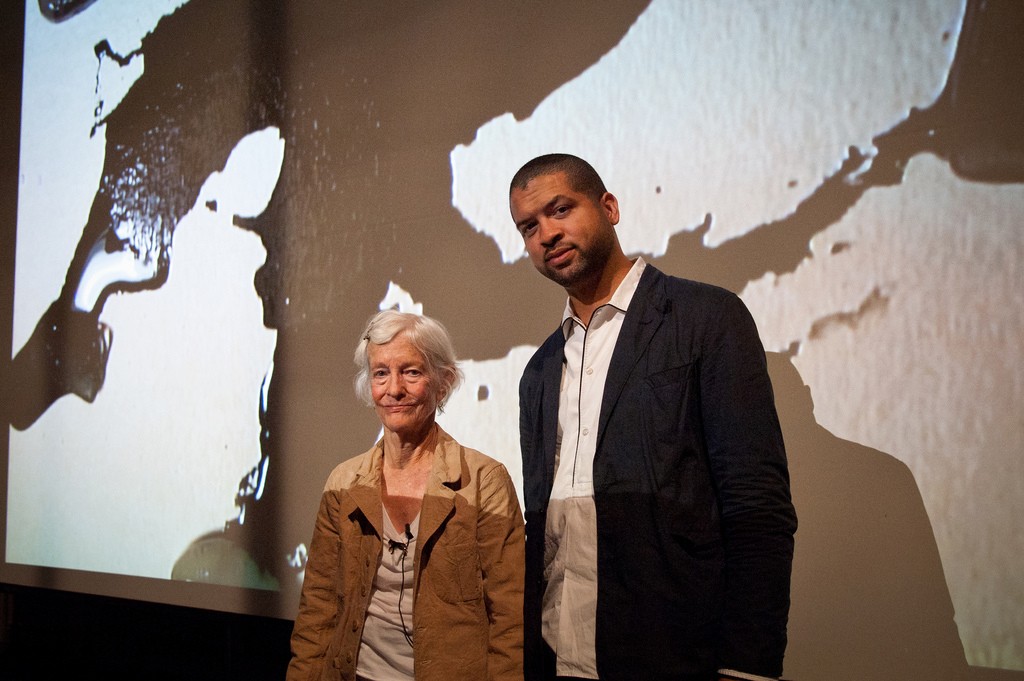 A man and a woman pose in front of a projected black and white ink image