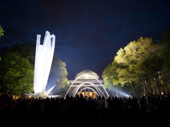 View of MIT dome at night with large illuminated inflatable sculptures in front and many people watching.