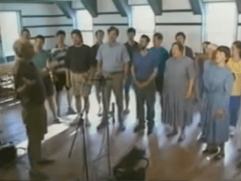 Blurry video still of a group of singers in rehearsal
