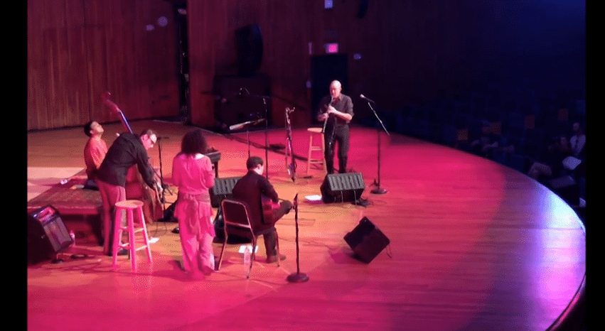 Five musicians perform on a large stage