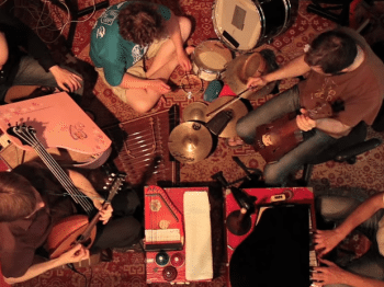 Overhead view of five people playing an assortment of miniature instruments.