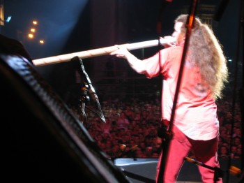 A man plays a long tube in front of a large audience