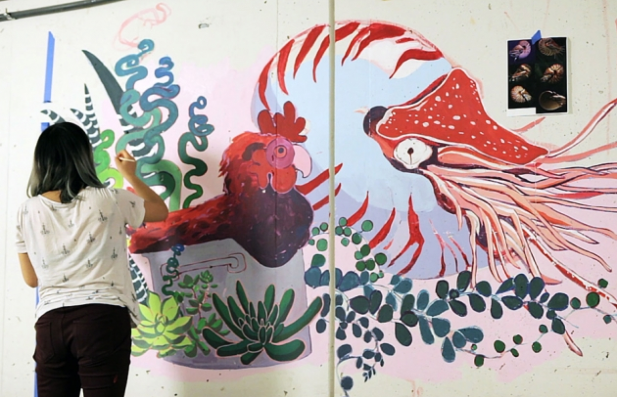 A student paints a colorful mural.