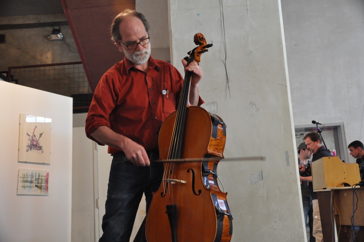 A man plays cello standing in an art gallery