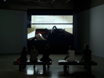 People watch a film in an art gallery.