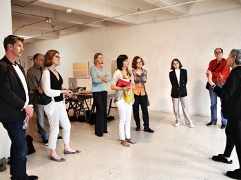 A guide speaks to a group of people in a gallery studio space.