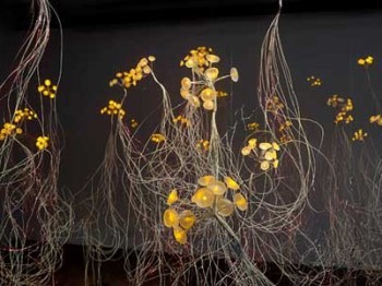 Sculpture made of clusters of flower-like yellow discs connected to long stiff metal wires.