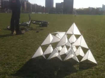 A kite made of many small white triangles on a green field.