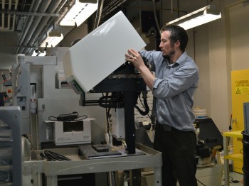 A man works with a large complex machine in a lab.