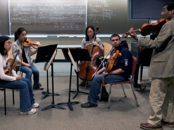 A string quartet rehearses with a professor in a classroom.
