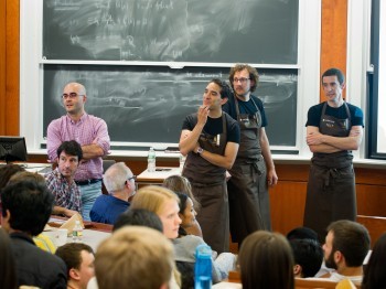 Three men in aprons present in a classroom.