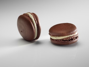 Two macaroons with brown pastry and white filling.