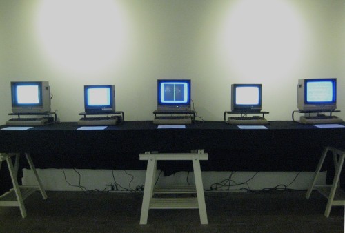 Nick Montfort’s five Commodore 64 programs running on five of the taupe keyboard-and-CPU units. Boston Cyberarts Gallery, 2014. Photo: Courtesy of the artist.  