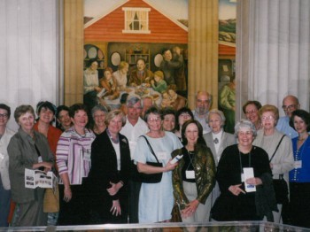 A group poses for a photo in front of a painting.
