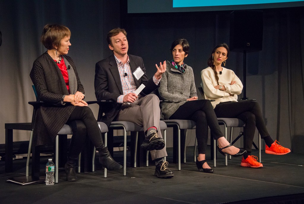A panel of four people on stage at a symposium.