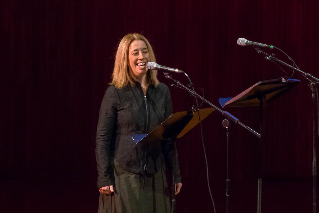 Elena Ruehr smiles as she speaks into a microphone on stage in Kresge Auditorium.