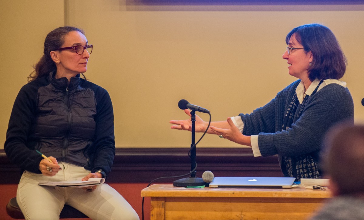 Two women in discussion at a symposium.