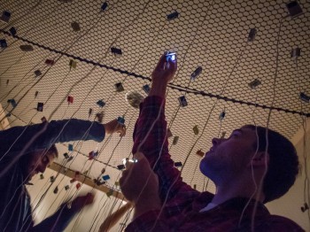 Students reach for one of several earbuds and ipods suspended above.