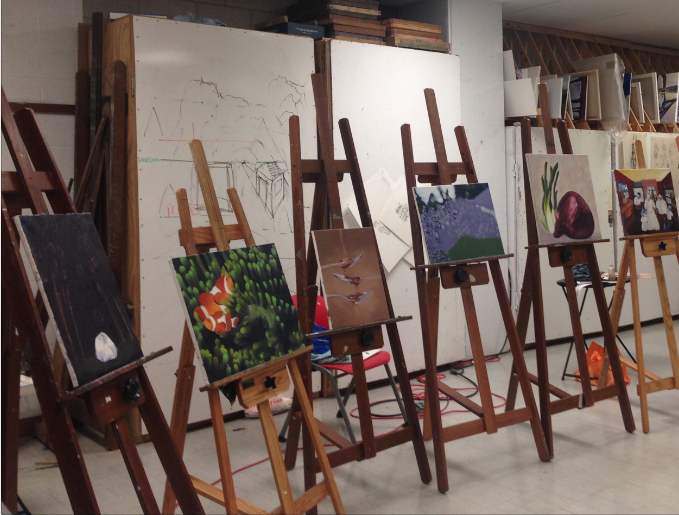 Easels with in-progress oil paintings in an art studio. 