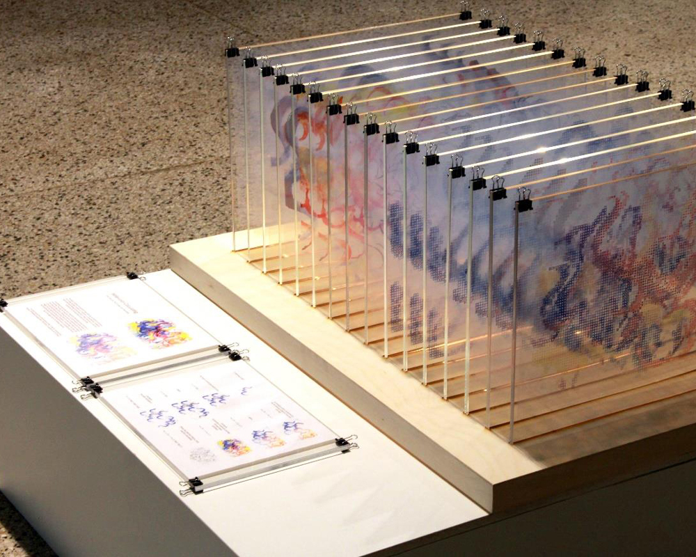 A series of glass plates with watercolor paintings are lined up in a row.