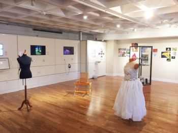 Installation view of an art exhibition in a gallery with hardwood floors, white walls and ceilings.