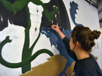A student paints a mural.