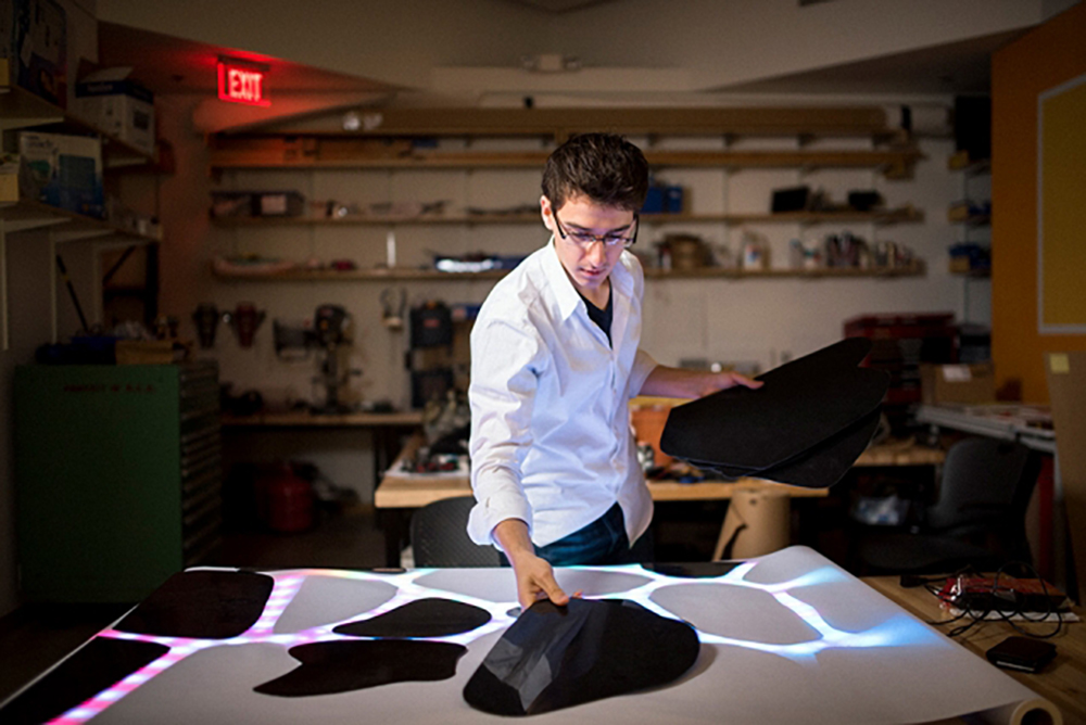 A student works on an illuminated panel.