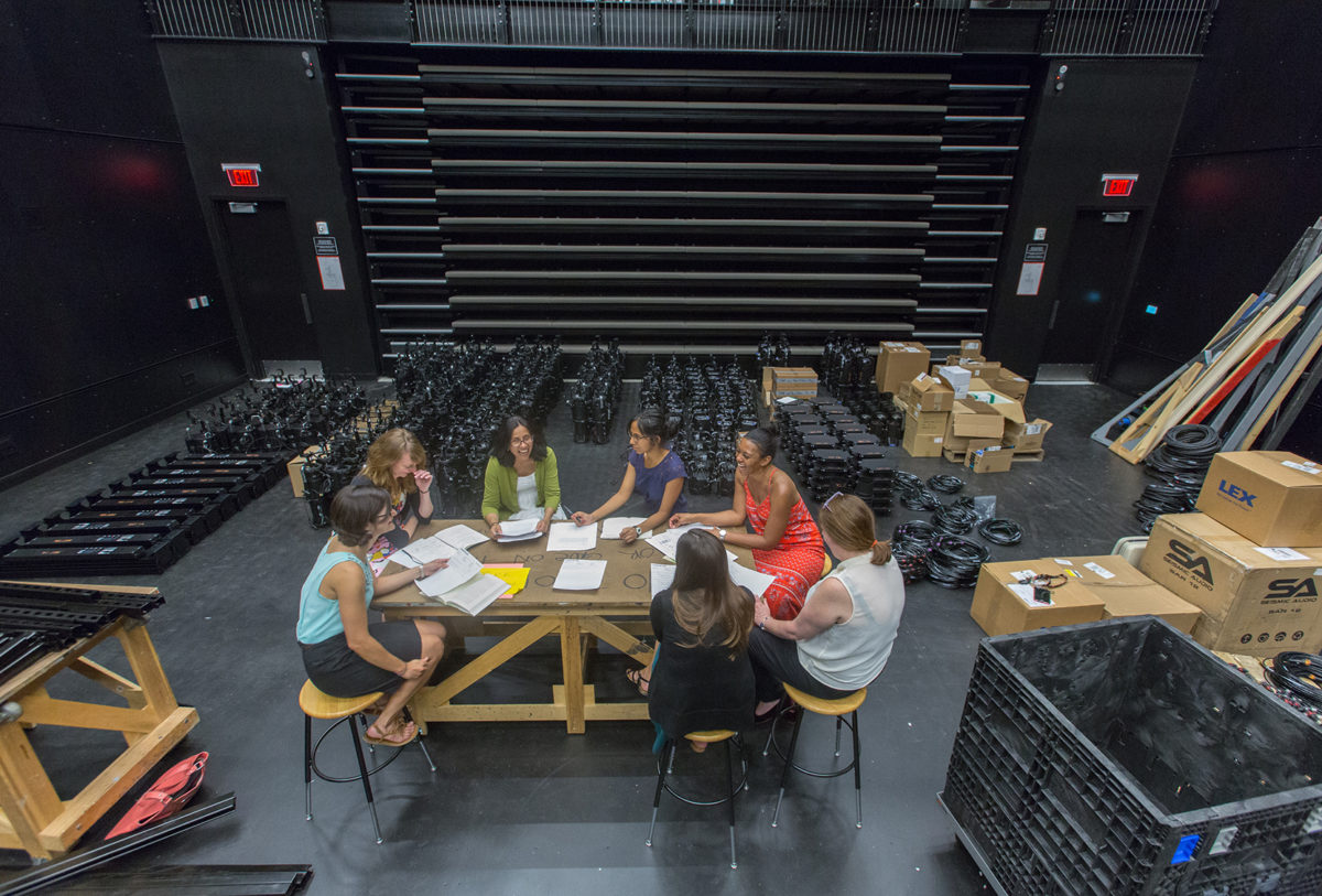 A group of women sit around a table in a theater.