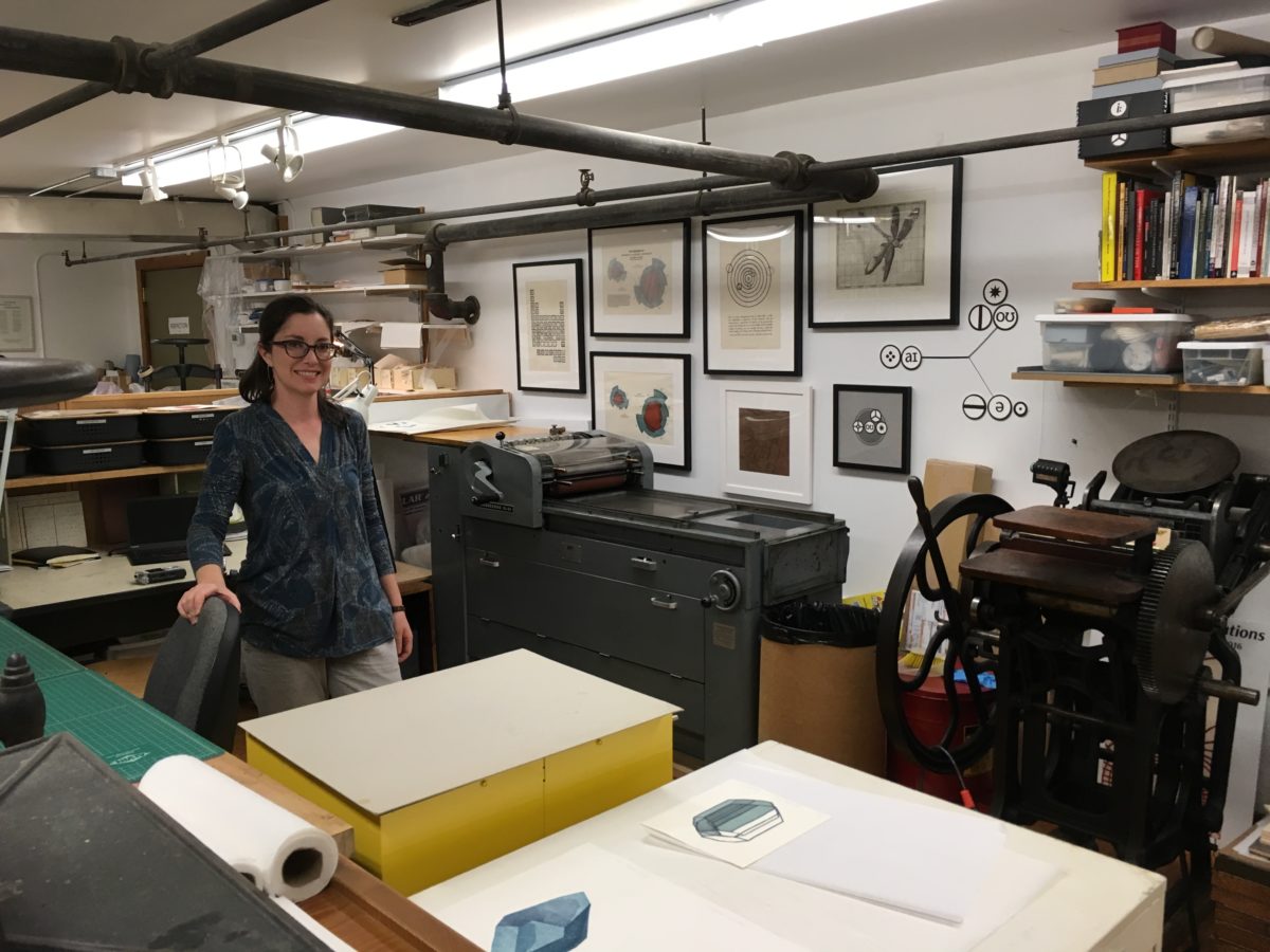 Sarah Hulsey in her studio. Pictured behind her are two of her presses and a selection of framed works. Photo: Sharon Lacey. 