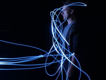 A performer appears surrounded by threads of light.