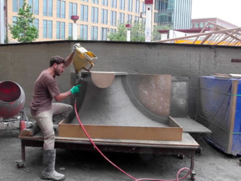 A man works with a machine on large cement sculptures.