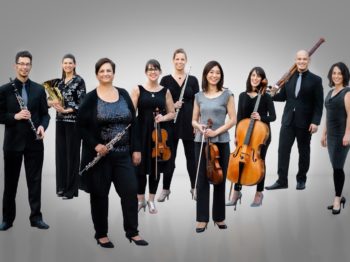 Nine musicians posing together with their instruments.